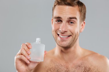 Genç adam sonra yüz tıraş losyonu uygulama gülümseyen