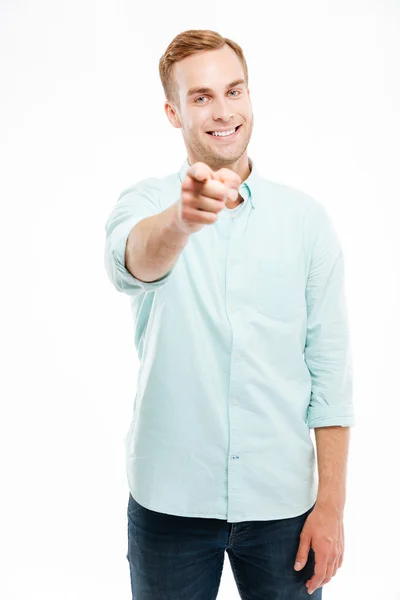 Jeune homme souriant et pointant vers la caméra sur fond blanc — Photo
