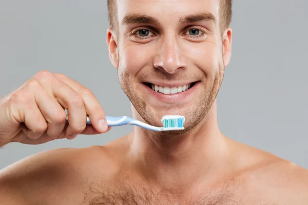 Primer plano joven feliz sosteniendo cepillo de dientes con pasta de dientes — Foto de Stock