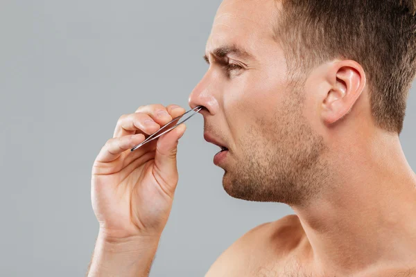 Vista laterale di un uomo che rimuove i peli del naso con le pinzette — Foto Stock