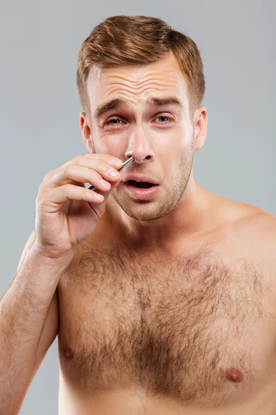 Retrato de primer plano del hombre quitando el pelo de la nariz con pinzas —  Fotos de Stock