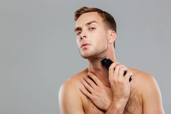Joven hombre feliz afeitándose con afeitadora eléctrica —  Fotos de Stock