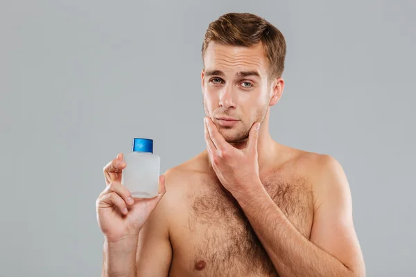 Hombre joven guapo aplicando loción después de afeitarse en la cara —  Fotos de Stock