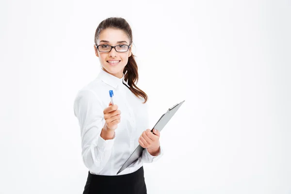 Дружелюбная молодая улыбающаяся деловая женщина с планшетом, указывающим ручкой на камеру — стоковое фото
