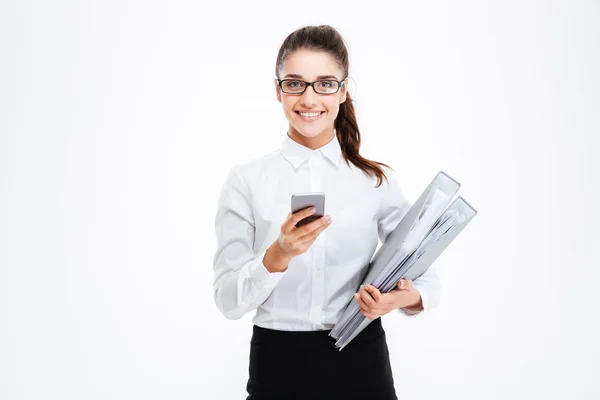 Χαρούμενη επιχειρηματίας σε γυαλιά κρατώντας φακέλους και χρησιμοποιώντας το κινητό τηλέφωνο — Φωτογραφία Αρχείου