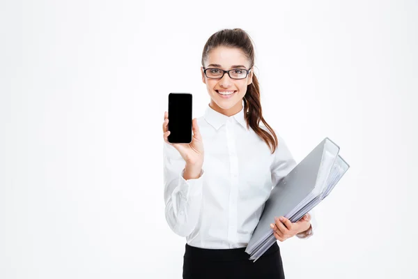 Lachende jonge zakenvrouw met mappen met leeg scherm mobiele telefoon — Stockfoto