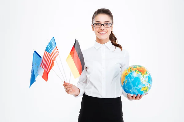 Joven empresaria sonriente sosteniendo banderas de países y del mundo — Foto de Stock