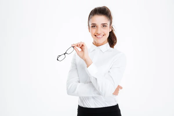 Fröhliche attraktive junge Geschäftsfrau steht und hält eine Brille — Stockfoto