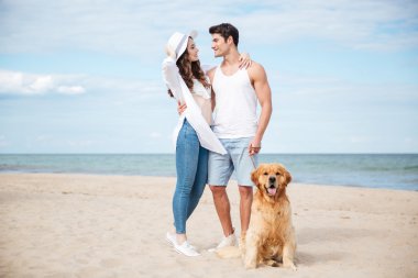 Mutlu çift köpek ile Sahilde yürürken sarılma