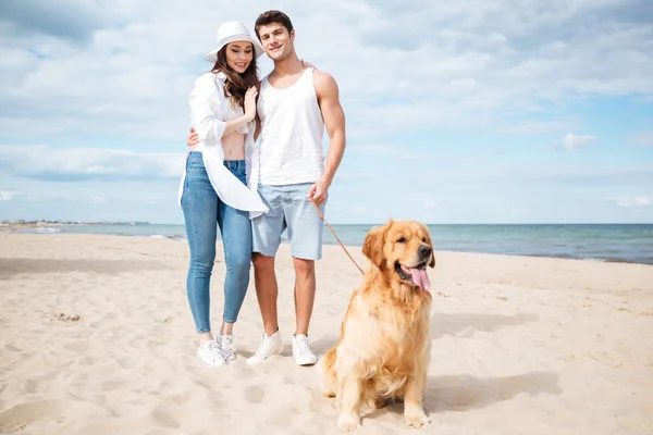 Par kramar och promenerar med hund på stranden — Stockfoto