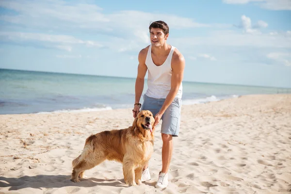 Man går och spelar med sin hund på stranden — Stockfoto