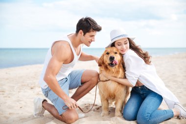 Çift oturma ve onların köpek sahilde sarılma