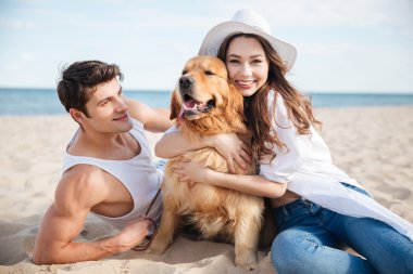 Gülümseyen iki köpek ile sahilde oturmuş aşk içinde