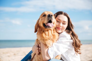 İhale gülümseyen genç kadın köpeğini sahilde sarılma
