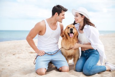 Köpek ile sahilde oturan Çift