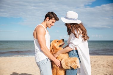 Aşık köpek ile sahilde oturup mutlu çift