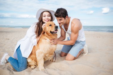 Aşık köpek ile sahilde oturan genç Çift