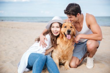 Aşık köpek ile sahilde oturan genç Çift