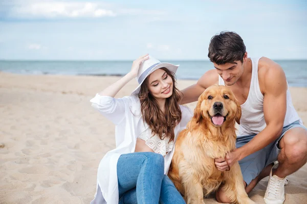 Unga älskande par leker med sin hund vid havet — Stockfoto