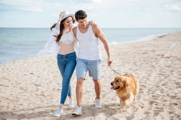 Genç çift ile onların köpek plaj boyunca çalışan