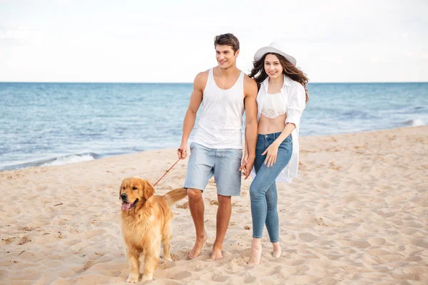 Romantic beautiful couple walking on the sea shore with dog