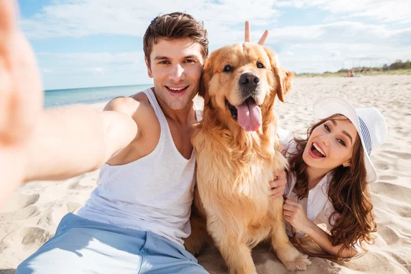 Young happy couple with dog taking a selfie