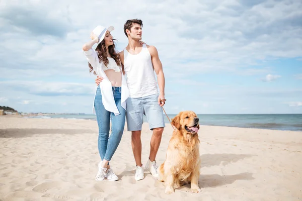 Casal caminhando com cão na praia no verão — Fotografia de Stock