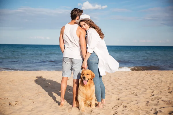 Пара проводить час разом на пляжі зі своїм собакою — стокове фото