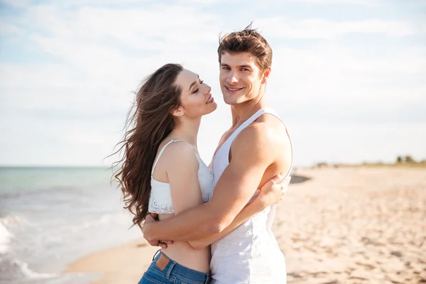 Casal de pé e abraçando na praia — Fotografia de Stock