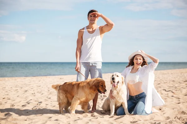 Jovem casal bonito de pé na costa do mar com cão — Fotografia de Stock