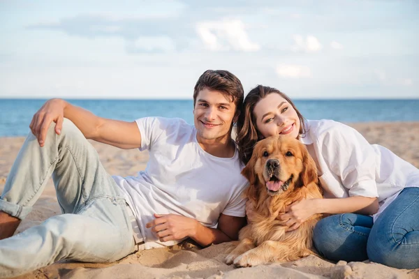 Echtpaar met hun hond liggen en ontspannen op het strand — Stockfoto