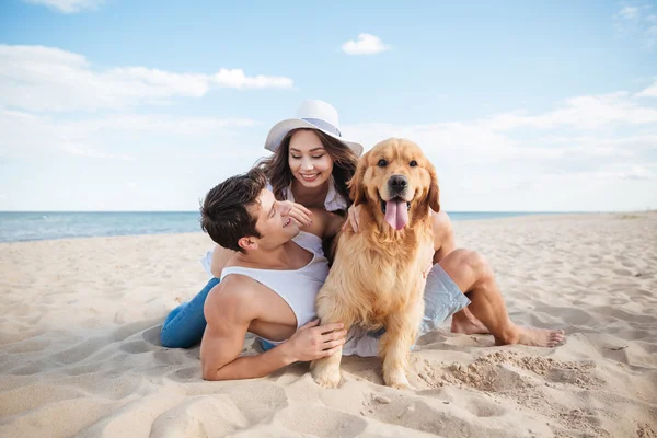 Krásný milující pár hrát s jejich psem u moře — Stock fotografie