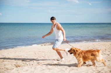 Gülümseyen ve köpeği ile plajda çalışan adam