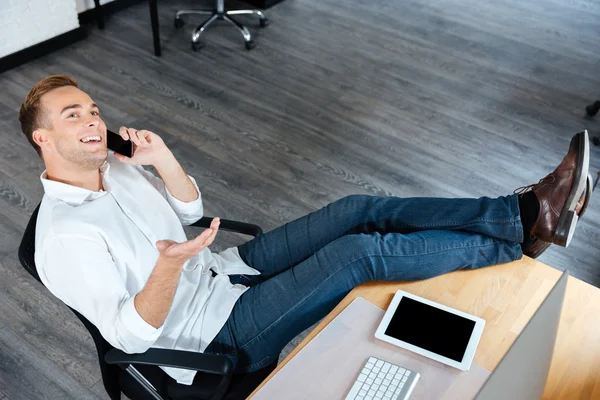 Pengusaha yang percaya diri duduk dan berbicara di telepon genggam di tempat kerja — Stok Foto