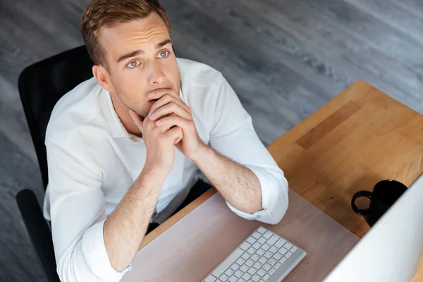 Hombre de negocios pensativo que trabaja con la computadora y el pensamiento en el lugar de trabajo — Foto de Stock