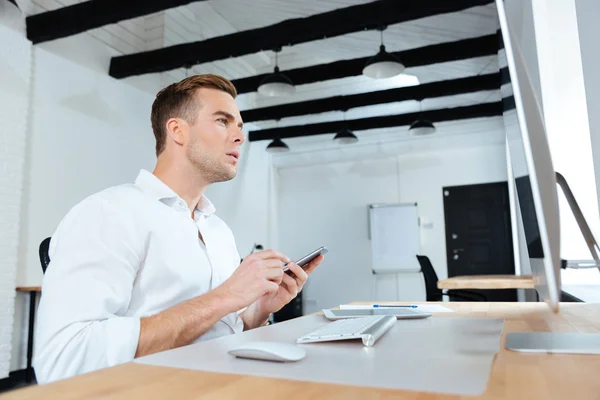 Zakenman met behulp van de computer en mobiele telefoon op werk — Stockfoto