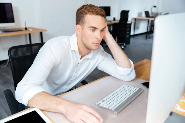 Cansado entediado jovem empresário que trabalha com computador no escritório — Fotografia de Stock