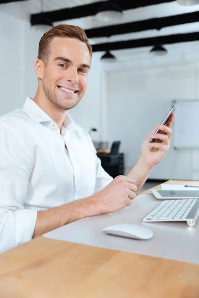 Heureux jeune homme d'affaires en utilisant smartphone dans le bureau — Photo