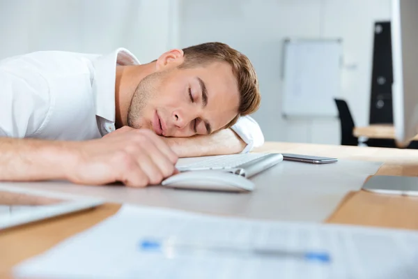 Agotado joven empresario fatigado durmiendo sobre la mesa —  Fotos de Stock