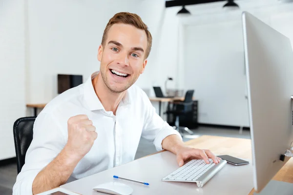 Jovem empresário alegre e bem sucedido celebrando o sucesso no escritório — Fotografia de Stock