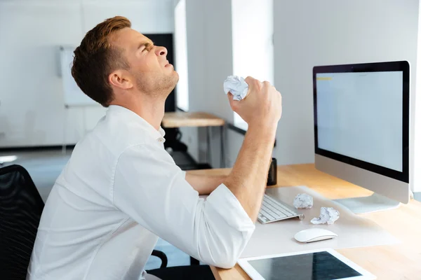 Angry stressed businessman sitting and crumpling paper in office — Stock Photo, Image