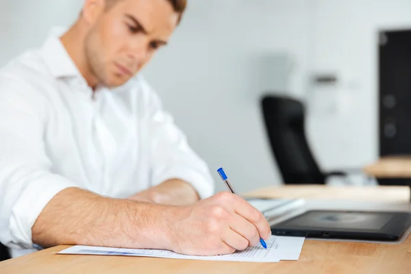 Zakenman zitten en schrijven aan de tafel — Stockfoto