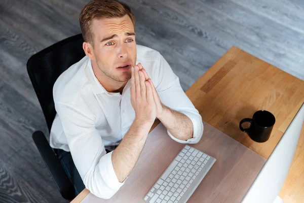 Smutny zdenerwowany młody biznesmen siedzi i modląc się w biurze — Zdjęcie stockowe