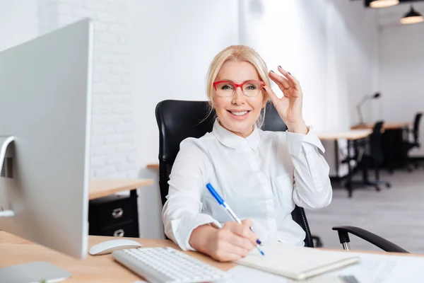 Retrato de uma mulher de negócios madura sorridente usando laptop no escritório — Fotografia de Stock