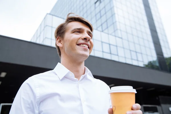 快乐的商人站在摩天大楼附近，喝咖啡 — 图库照片