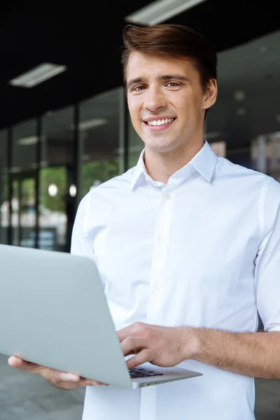 Empresário de pé e trabalhando com laptop — Fotografia de Stock