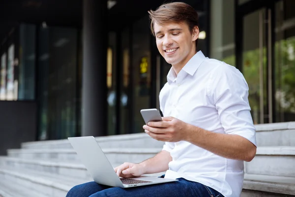 Empresario que usa teléfono móvil y portátil al aire libre — Foto de Stock