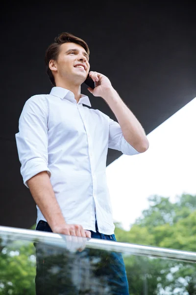 Feliz joven empresario confiado de pie y hablando por teléfono móvil — Foto de Stock