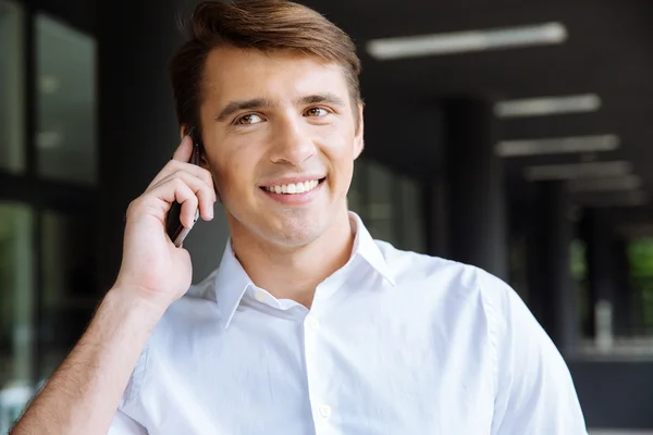 Happy businessman in white shirt talking on cell phone outdoors — Stock Photo, Image