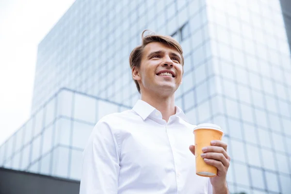 Empresario de pie cerca del centro de negocios y beber café — Foto de Stock